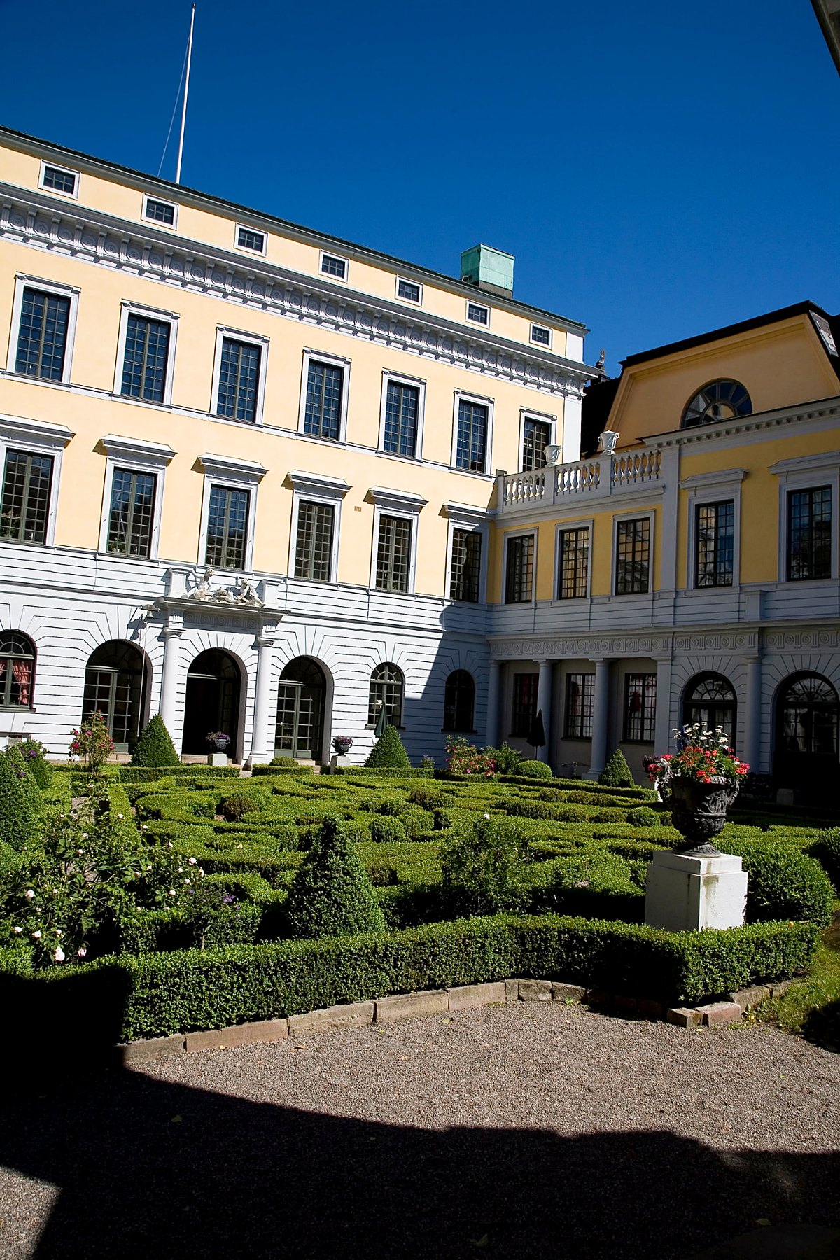 Innergård med barockträdgård framför gulputsat palats i Stockholm