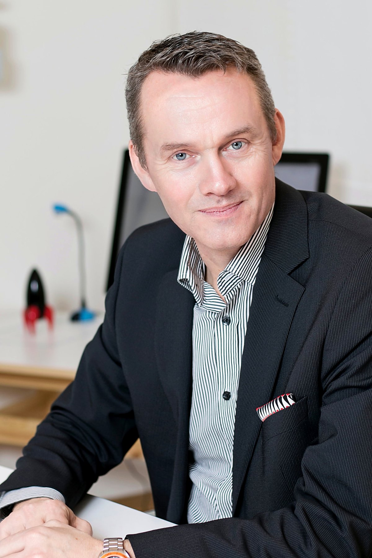 Ledarporträtt av man i mörk kostym med randig skjorta på kontor