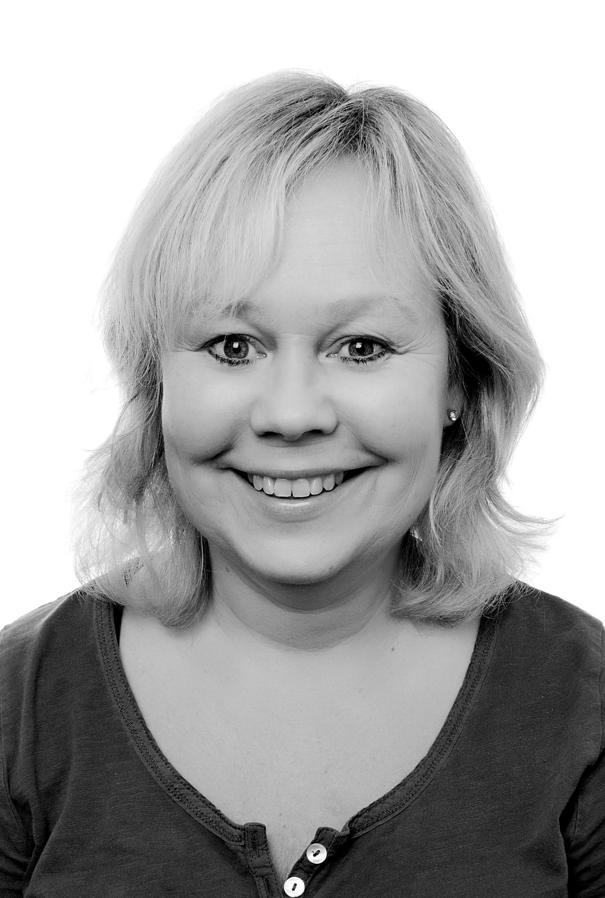 Svartvitt studioporträtt av leende kvinna mot vit bakgrund